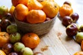 Beautiful shallow focus shot of a basket of mandarins on a wooden table surrounded by plums