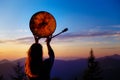 Beautiful shamanic girl playing on shaman frame drum in the nature.