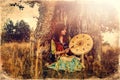 Beautiful shamanic girl playing on shaman frame drum in the nature, old photo effect. Royalty Free Stock Photo