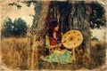 Beautiful shamanic girl playing on shaman frame drum in the nature, old photo effect. Royalty Free Stock Photo