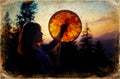 Beautiful shamanic girl playing on shaman frame drum in the nature, old photo effect. Royalty Free Stock Photo