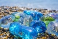 Beautiful shape glass and stones on the seashore. Azure clear sea water with waves. Green, blue shiny glass with multi