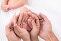 Beautiful shape hands of father, mother, hold tiny newborn baby feet leg on white bed with love, care, family safety and Royalty Free Stock Photo