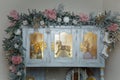 Beautiful shebby chic cupboard decorated with artificial snowy fir branches, icy roses, rocking horse toy, golden Christmas