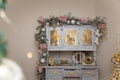 Beautiful shebby chic cupboard decorated with artificial snowy fir branches, icy roses, rocking horse toy, golden Christmas