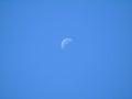 Beautiful shimmering half moon hiding behind creamy blue sky