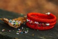 Beautiful, shiny, color bracelet with large beadwork beads. On a special stand for jewelry. Beads are scattered on a wooden table Royalty Free Stock Photo