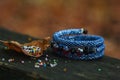 Beautiful, shiny, color bracelet with large beadwork beads. On a special stand for jewelry. Beads are scattered on a wooden table Royalty Free Stock Photo