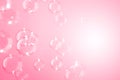 Beautiful shiny transparent soap bubbles floating on a pink background