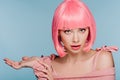 Beautiful shocked girl in pink wig posing with shrug gesture isolated