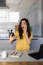 Beautiful shocked woman sitting indoors laptop computer chatting by mobile phone Royalty Free Stock Photo