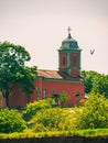 Beautiful shot of a bird flying near to small rural church under cloudy sky on a sunny day Royalty Free Stock Photo