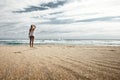 Beautiful shot of a blonde female standing on the seashore fixing her hair