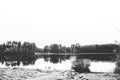 Beautiful shot of a boat on the water near the shore with trees in the distance in black and white Royalty Free Stock Photo