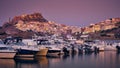 Beautiful shot of boats on the water with buildings on the hill and a purple sky in the background