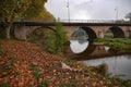 Beautiful shot of a bridge reflecting on a river surface during autumn Royalty Free Stock Photo