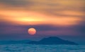 Beautiful shot of a bright sunset sky with a glowing sun over water with mountains in Athens, Greece Royalty Free Stock Photo