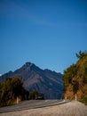 Beautiful shot of a car on the road to Glenorchy with a mountain in the background taken at sunrise on a winter day in Queenstown Royalty Free Stock Photo