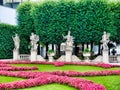 Beautiful shot of a city park with statues and a green lane decorated with rosy flowers Royalty Free Stock Photo