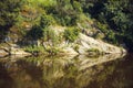 Beautiful shot of a cliff surrounded by lush nature reflecting on a lake