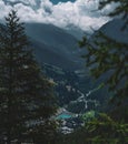 Beautiful shot of clouds on mountains of Parco Naturale Val Troncea, Italy seen through fir trees