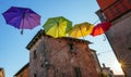 Beautiful shot of the colorful umbrellas hanging on the road between houses Royalty Free Stock Photo