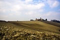 Beautiful shot of a dry grassy field with a house on top of the hill under a blue cloudy sky Royalty Free Stock Photo