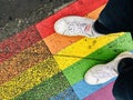 Beautiful shot of a female in white sneakers standing on the ground with the colors of pride flag Royalty Free Stock Photo