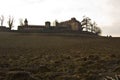 Beautiful shot of a field with a castle in the distance under a cloudy sky Royalty Free Stock Photo