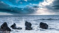 Beautiful shot of foamy waves crashing on the rocks under a cloudy sky in South Tyneside