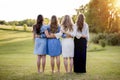 Beautiful shot of four girls with there arms around each other standing in a grassy field