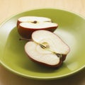 Beautiful shot of the fresh red apple in half on a green plate Royalty Free Stock Photo