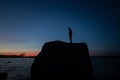 Beautiful shot of a male standing on a big rock and admiring the sunset above the lake Royalty Free Stock Photo