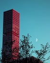 Beautiful shot of a modern high-rise building and half-moon against a blue sky Royalty Free Stock Photo