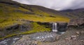 Beautiful shot of a mountainous landscape with a small waterfall with an overcast sky Royalty Free Stock Photo