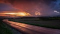 Beautiful shot of a narrow curvy road in the countryside in the middle of a field at sunset Royalty Free Stock Photo