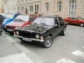 Beautiful shot of an old-fashioned black vintage car with other cars in the background on the street Royalty Free Stock Photo