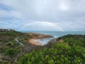Beautiful shot of a pathway in the beach with a rainbow in the cloudy sky Royalty Free Stock Photo