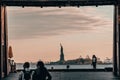 Beautiful shot of people walking near the water with a view of the Statue of Liberty in NYC
