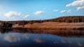 Beautiful shot of a reflection of cloudy skies in the lake with rocky hills in the background