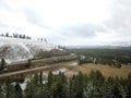 Beautiful shot of roads on the side of a snowy mountain surrounded by trees under a cloudy sky Royalty Free Stock Photo