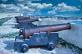 Beautiful shot of a row of cannons with a cloudy blue sky Royalty Free Stock Photo