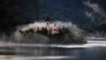 Beautiful shot of a rural village on a shore surrounded by fog in Slovenia Royalty Free Stock Photo