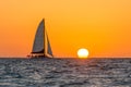 Beautiful shot of a sailboat approaching the sun setting above the horizon over the Gulf of Mexico