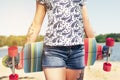 Beautiful shot of young girl in shorts walking with colorful longboard in sunny weather. Leisure. Healthy lifestyle