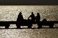 Beautiful shot of silhouettes of people hanging around on a wooden dock over a pier at sunset Royalty Free Stock Photo