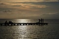 Beautiful shot of silhouettes of people hanging around on a wooden dock over a pier at sunset Royalty Free Stock Photo