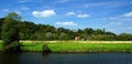 Beautiful shot of a small house around green trees and grassy field on a cloudy daylight