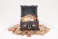Beautiful shot of a small treasure box full of coins with a white color in the background