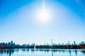 Beautiful shot of a sun glowing over the buildings, trees and lake water Royalty Free Stock Photo
